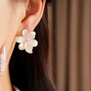 Elegant pink gradient flower stud earrings with zircon center shown on model's ear