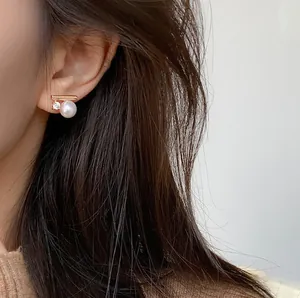 Close-up view showing a minimalist gold stud earring with pearl and zircon stone