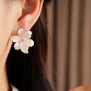 Close-up detail showing a pink oil-drip flower earring with a zircon center on a model's ear