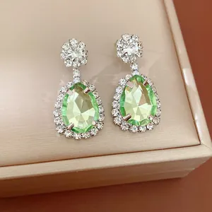 Close-up detail of light green teardrop crystal earrings with rhinestone halo.