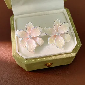 Close-up of pink enamel flower stud earrings with zircon centers in a green velvet box