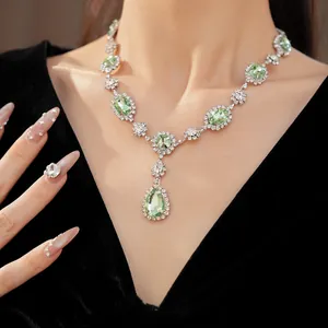 Close-up of court style necklace with teardrop and oval green rhinestones on neck