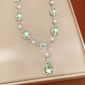 Close-up of elegant green teardrop pendant necklace with sparkling crystal halo detailing
