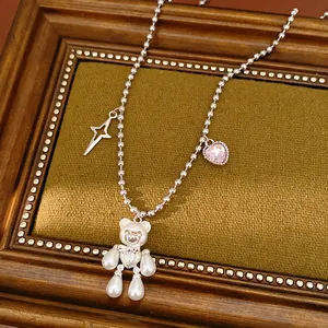 Close-up of pearl bear necklace with star and pink heart zircon charms.