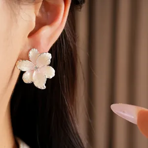 Close-up detail of elegant pink enamel flower stud earrings with zircon on an ear