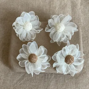 Dettaglio di orecchini a fiore in rete oversize con centro intrecciato su vassoio rustico.