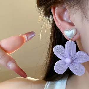 Primo piano di orecchino a fiore in chiffon lavanda con perla a cuore su modella