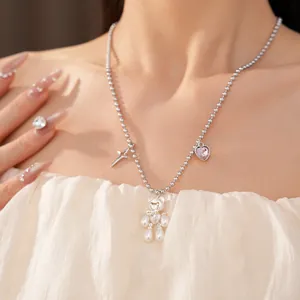 Detailed view of silver ball chain necklace featuring pearl bear star and pink heart charms