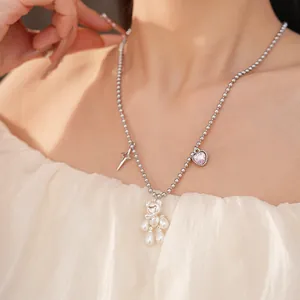 Detailed macro shot of a cute silver ball chain necklace with a pearl teddy bear pendant.