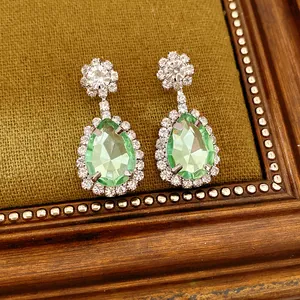 Detailed view of vintage royal style drop earrings with green pear-shaped stones.