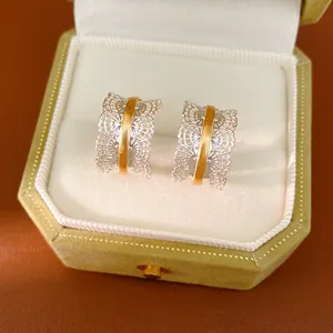 Detalle de pendientes de encaje en forma de C en oro y plata en una caja de joyas.