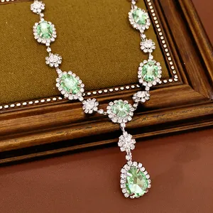 Detailed view of court style necklace with green oval and teardrop shape gemstones