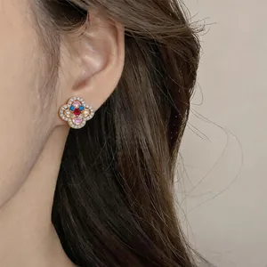 Detail view of vintage-style floral stud earring with colorful zircon stones on model's ear.