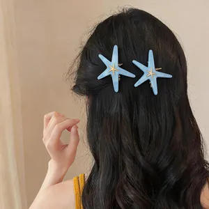 Vue détaillée de barrettes étoile de mer en résine bleue stylisées sur cheveux noirs ondulés.