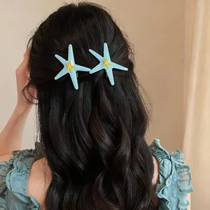 Détail de pinces à cheveux étoile de mer en résine bleue sur cheveux sombres ondulés