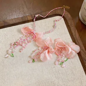 Macro detail of handmade pink fabric flower necklace and earrings set with beads