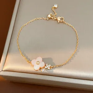 Dettaglio macro di un bracciale a fiore rosa con zirconi brillanti su catena d'oro
