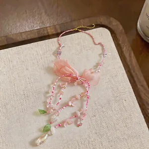 Exquisite close-up of pink beaded necklace featuring fabric bow and dainty floral charms