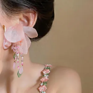 Detailed close-up of elegant pink fabric flower drop earrings with beads on model