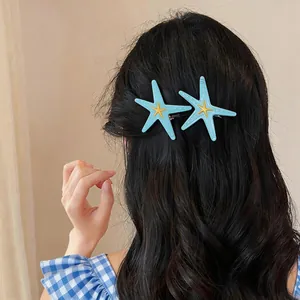 Vue détaillée de deux pinces à cheveux étoile de mer bleues sur des cheveux noirs ondulés