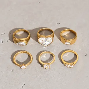 Detailansicht von sechs goldenen Edelstahlringen mit Kristallen auf grauem Stein