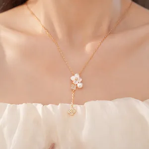 Primo piano di una collana a fiori di ciliegio dorata con perla e zircone su modella