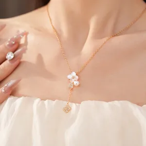 Primo piano di una collana a fiori di Sakura dorata con perla e zirconi su modella