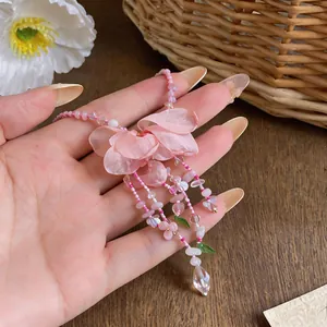 Close-up of pink fabric flower pendant necklace with delicate beaded tassels
