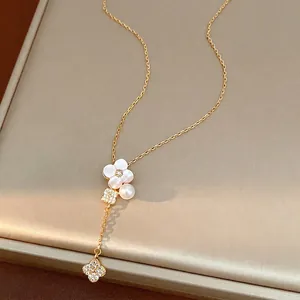 Dettaglio della collana fiore di ciliegio dorata con fiore in conchiglia, perla e quadrifogli