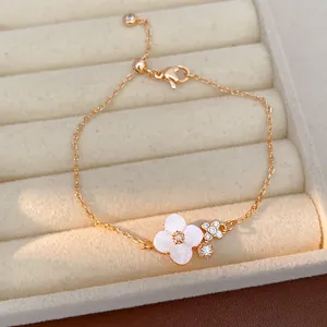Elegante bracciale a fiori di ciliegio in oro con fiore in conchiglia bianca e zirconi