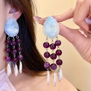 Vintage boho style tassel earrings featuring blue resin drops and purple beads