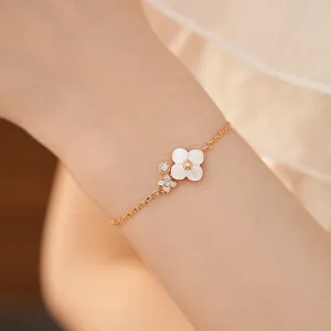 Dettaglio di un delicato bracciale in oro con fiore in madreperla bianca e zirconi lucidi