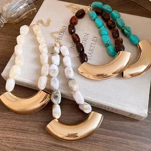 Detail view of chunky acrylic beaded necklaces with curved gold-tone metal pendants