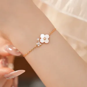 Dettaglio di un braccialetto a fiore rosa ciliegio con zirconi brillanti su un polso.