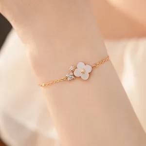 Vista dettagliata di bracciale con fiori rosa ciliegio e zirconi su catena dorata.