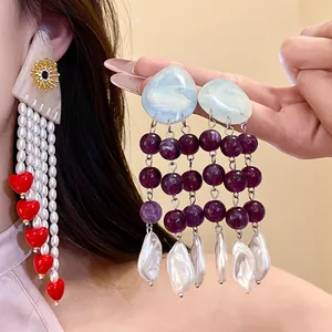 Close-up of elegant resin pearl tassel earrings with purple beads and heart accents