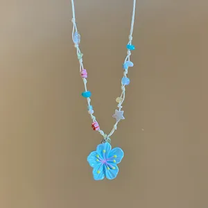 Detailansicht einer bunten gewebten Halskette mit blauem Blumenanhänger Motiv