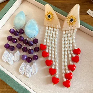 Detail of retro ethnic resin pearl tassel earrings with red heart and sun motifs.