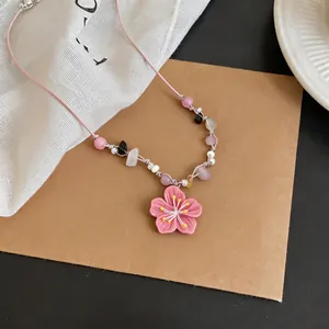 Detailed view of a pink cherry blossom pendant necklace with colorful beads on a pink cord