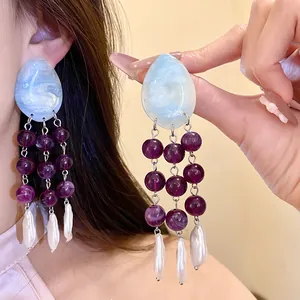Macro detail showing light blue resin and purple bead tassels on ethnic style earrings.