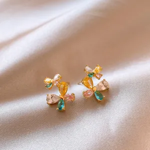 Detailed macro view of butterfly earrings with vibrant colorful zircon stones on soft satin