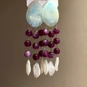 Close-up of ethnic style tassel earrings with marbled resin beads and white baroque pearls