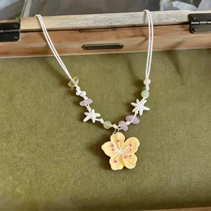 Detail of handmade colorful floral necklace with yellow pendant and star beads