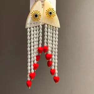 Detailed view of vintage resin pearl tassel earrings with vibrant red heart charms