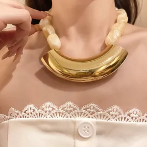 Detailed view of chunky cream marble acrylic beads and curved gold metal pendant