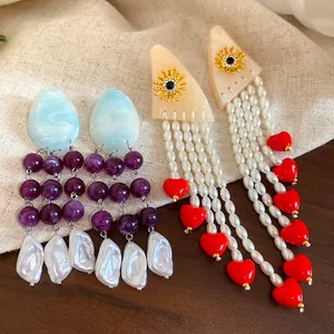 Detailed macro view of resin pearl tassel earrings with heart and sun motif designs
