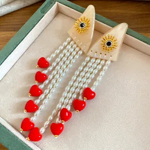 Exquisite detail of resin pearl tassel earrings featuring bright red heart-shaped charms