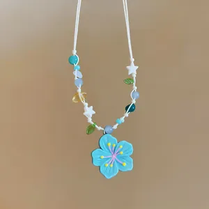 Close-up of a blue flower pendant necklace with colorful stars and leaf beads
