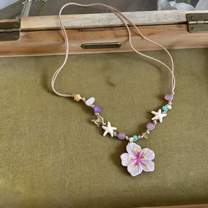Detail shot of a dopamine-style necklace featuring a large purple flower pendant and colorful beads