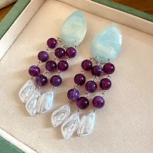 Detailed view of vintage tassel earrings with purple beads and white baroque pearls